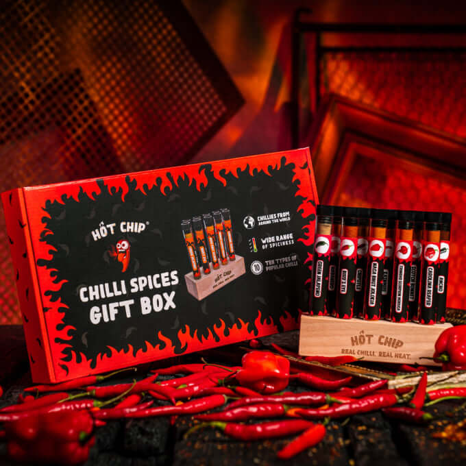 Coffret cadeau épices piquantes Hot Chip 10pcs avec sauce piquante, sur fond de cuisine rouge et noire.